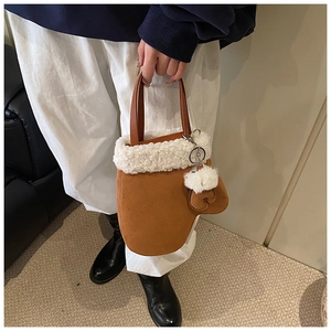 Detail of creative mitten-shaped brown suede bucket bag with white faux fur trim and heart