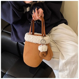 Detail of creative glove-shaped plush handbag with white faux fur trim and pom-pom charm