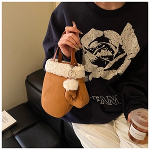 Close-up of brown suede mitten-shaped handbag with white faux shearling trim and cute charm