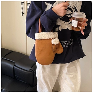 Detail view of brown suede mitten-shaped bucket bag with plush white faux fur trim and charm
