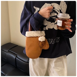 Detail of creative glove-shaped crossbody bag with white faux fur trim and pom-pom charm