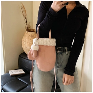 Close-up of pink glove-shaped crossbody bag with white faux fur trim and shoulder strap