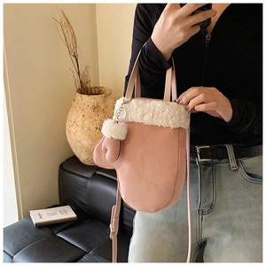 Chic pink glove-shaped handbag with white faux fur trim shown in a cozy interior