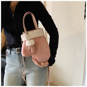 Close-up of a pink glove-shaped bucket bag with white plush trim and shoulder strap