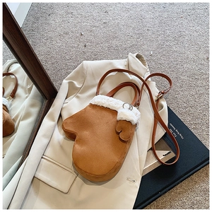 Creative brown suede glove-shaped handbag with white faux fur trim on a beige blazer