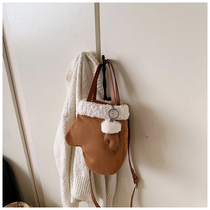 Detail of mitten-shaped faux suede crossbody bag with soft white faux fur trim and strap