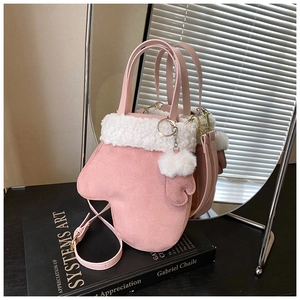 Detail of pink glove-shaped crossbody bag featuring white faux fur trim and plush ball charm