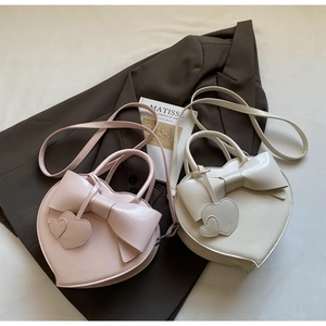 Détail de sacs à main tendance en forme de cœur avec grands nœuds et breloques de cœur