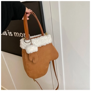 Detail of glove-shaped suede bag with white faux fur trim and plush ball charm