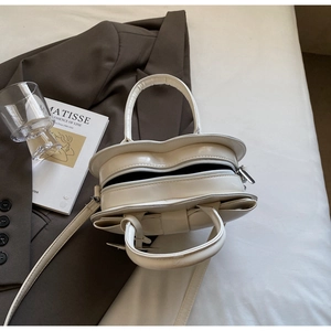 Détail d'un sac à main blanc en forme de cœur en cuir verni brillant avec fermeture