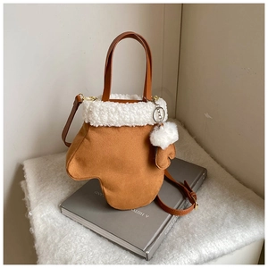 Detail of tan suede glove-shaped handbag featuring plush white faux fur trim and mini charm