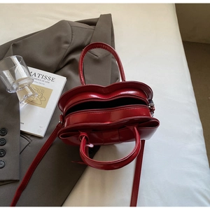 Détail d'un sac à main rouge en forme de cœur en cuir verni avec bandoulière