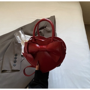 Détail du sac rouge en cœur rouge avec grand nœud et breloque cœur en décor lifestyle
