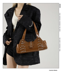Gros plan d'un sac bandoulière marron punk avec rivets argentés et boucles en métal