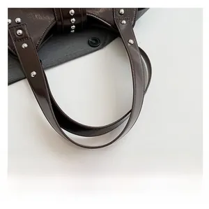 Gros plan de la fixation des anses sur le sac en cuir verni marron foncé avec rivets
