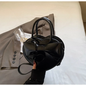 Détail du sac à main en cuir noir en forme de cœur avec grand nœud et bandoulière