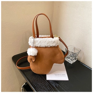Detail of creative glove-shaped brown suede bucket bag with white faux fur trim and gold hardware