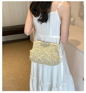 Detail of hand-woven beige straw crossbody bag with gold chain strap and vintage metal clasp