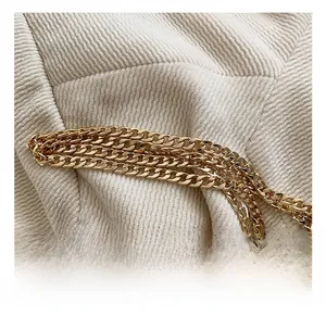 Close-up of premium gold metal chain strap on a woven clutch bag with white texture