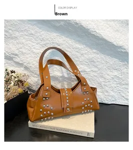 Gros plan d'un sac à main marron en similicuir avec rivets argentés sur pierre blanche