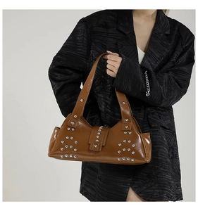 Détail d'un sac à bandoulière en cuir brillant marron avec rivets punk argentés