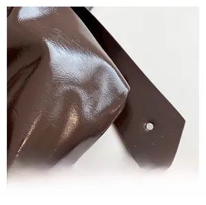 Detail der dunkelbraunen Lackleder-Tasche mit modischen Falten und silberner Nietendeko
