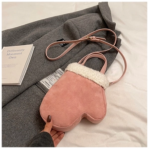 Close-up of pink mitten-shaped crossbody bag with white faux shearling trim on grey coat