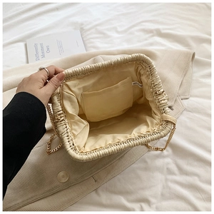 Interior view of straw woven clutch bag featuring fabric lining and golden chain strap