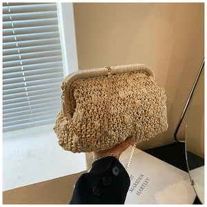 Detail of woven straw clutch with wave texture and elegant gold metal chain strap