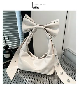 Detail einer weißen Schleifen-Handtasche mit silbernen Nieten im Metallregal