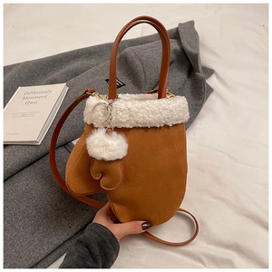 Detail view of winter brown mitten shaped bag with white faux fur trim and pom-pom charm