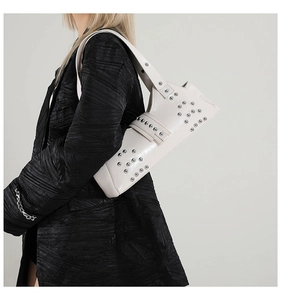 Détail du sac à bandoulière punk blanc avec rivets métalliques sur blazer noir