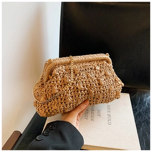 Detail of hand-woven straw clutch featuring textured weave and gold chain strap