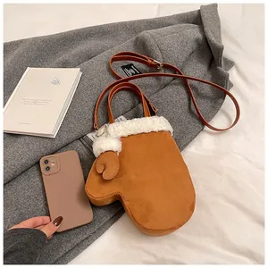 Detail of a brown glove-shaped suede bag with white fleece trim and a leather strap