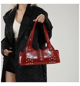 Détail d'un sac en cuir verni rouge avec des clous punk argentés et de longues anses