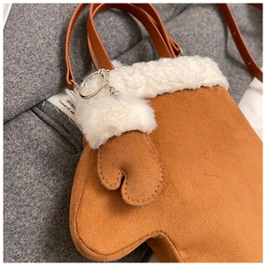 Detail of creative brown glove-shaped crossbody bag with white plush trim and suede texture