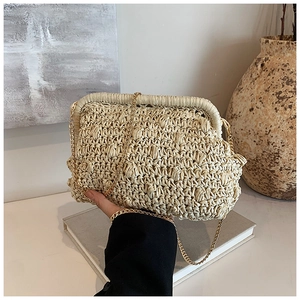 Detail of handmade straw clutch with woven texture and gold chain strap
