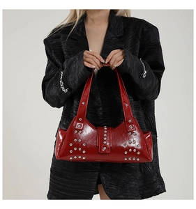 Détail du sac à main en cuir verni rouge avec rivets argentés et boucle de style punk