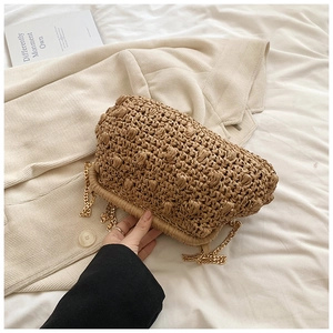 Detailed view of woven cloud bag with raffia texture and detachable gold chain strap