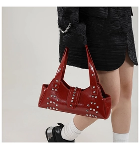 Détail du sac baguette en cuir verni rouge avec rivets argentés et style punk