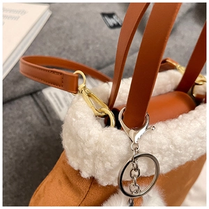 Macro detail of brown suede crossbody bag featuring white lamb wool trim and gold hardware