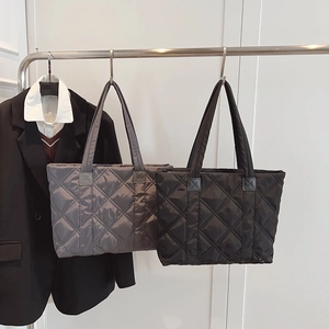 Quilted tote bags in dark grey and black nylon displayed on a metal rack