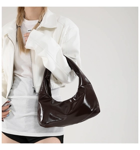 Detail of deep brown patent leather crescent bag featuring silver rivet decorations