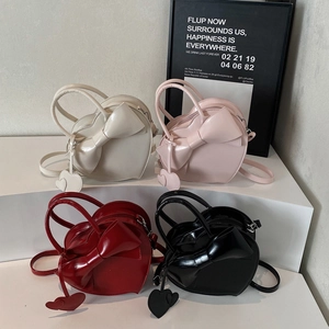 Sacs à main en forme de cœur avec nœud en blanc, rose, rouge et noir sur socle