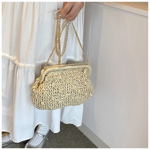 Macro shot of a cream woven clutch featuring bobble texture and a gold metal chain strap