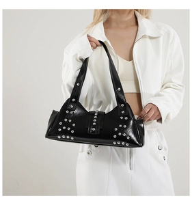 Détail du sac sous l'aisselle en cuir verni noir avec des rivets punk sur bandoulière