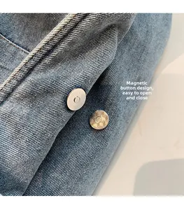 Detail of magnetic snap closure on light blue denim handbag with silver hardware
