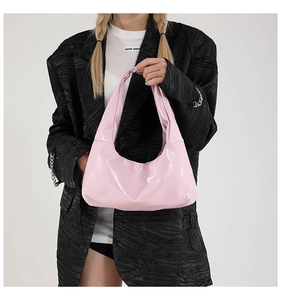 Detail of pink patent leather hobo bag with glossy finish and ruched handle design