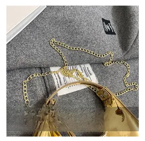 Détail du sac croissant doré avec finition miroir lisse et bandoulière en chaîne