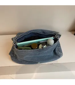 Spacious interior of denim chain bag showing storage for tablet, phone, and daily items
